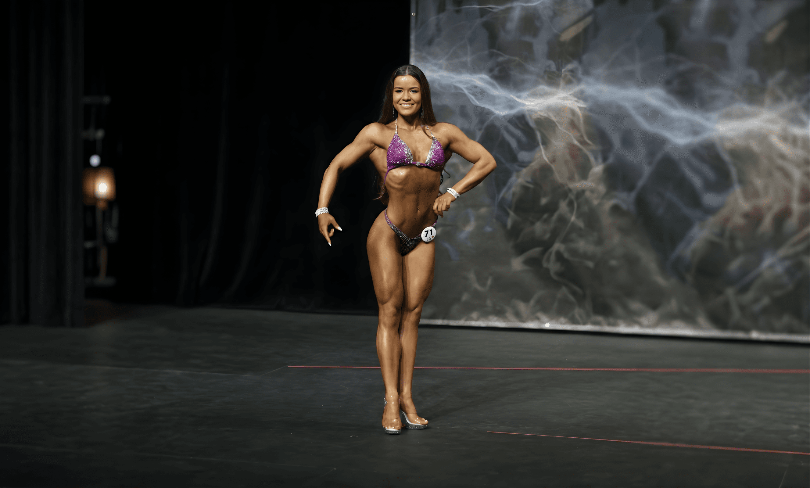 Maddie competing on stage at a figure bodybuilding competition